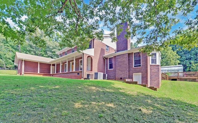 back of house with central AC unit, a deck, and a lawn