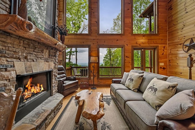 living room with a towering ceiling, wood finished floors, wooden walls, and a fireplace