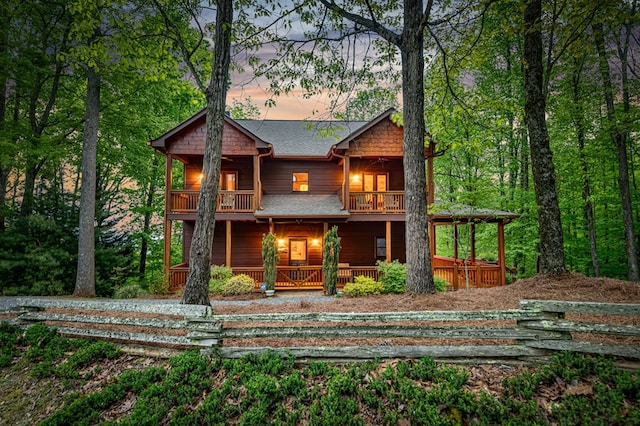 back of property featuring a porch, roof with shingles, and a balcony