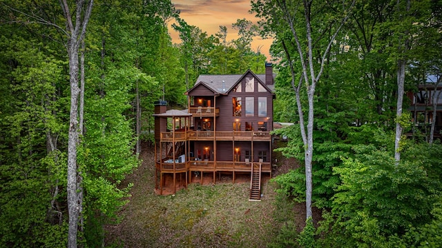 rear view of house with a deck, a chimney, a balcony, and stairs