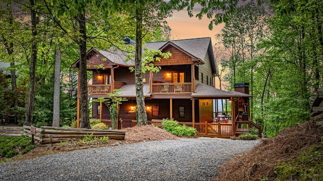 view of front of property featuring a shingled roof, a porch, and a balcony