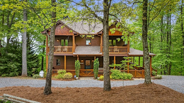 view of front of house featuring a porch, roof with shingles, and a balcony