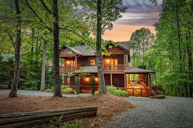 back of property with a porch, a balcony, and roof with shingles