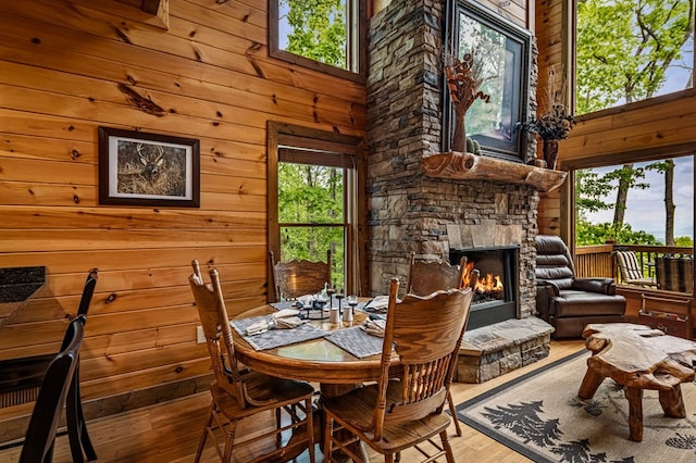 dining area featuring wood-type flooring, wood walls, and a fireplace