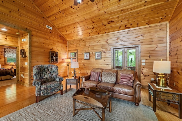 living area featuring wooden walls, visible vents, wooden ceiling, wood finished floors, and vaulted ceiling