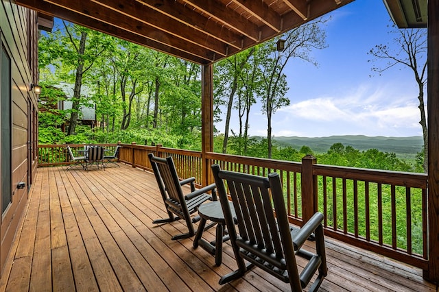 wooden terrace featuring a mountain view and outdoor dining space