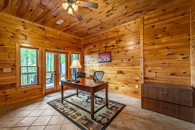 office featuring a ceiling fan, french doors, visible vents, light tile patterned floors, and wooden walls