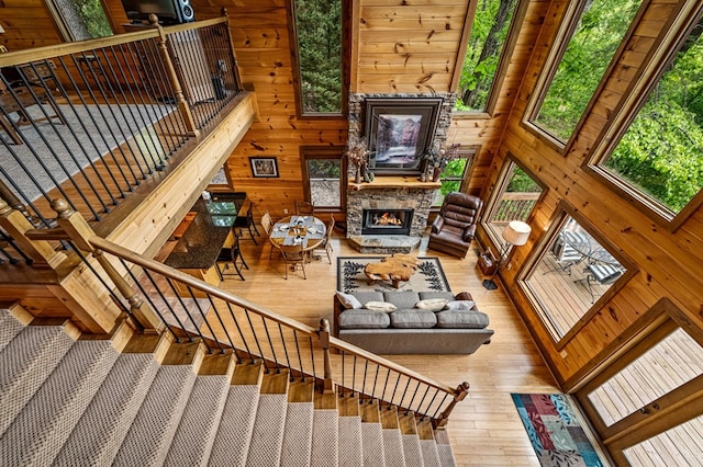 living area with wooden walls, stairway, a fireplace, and hardwood / wood-style flooring