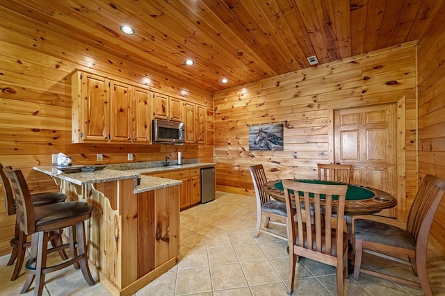 kitchen with a peninsula, light stone countertops, recessed lighting, wooden ceiling, and stainless steel appliances