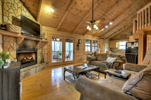 living room featuring beam ceiling, a stone fireplace, wooden walls, and wood ceiling