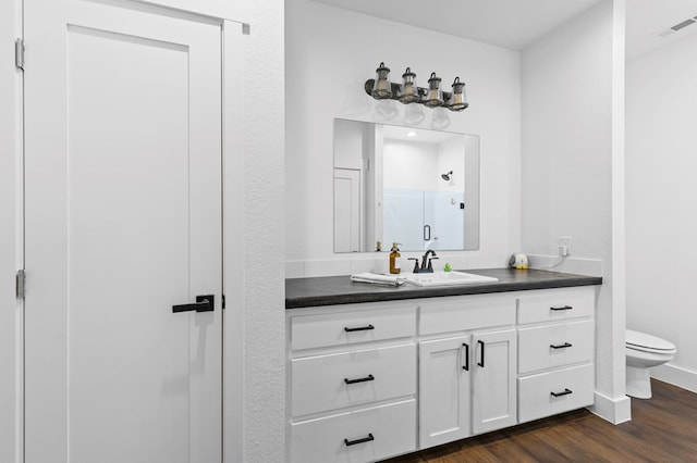 bathroom featuring vanity, hardwood / wood-style flooring, toilet, and walk in shower