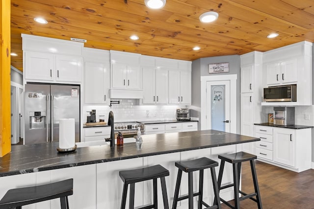 kitchen with white cabinetry, stainless steel appliances, dark hardwood / wood-style flooring, and a kitchen breakfast bar