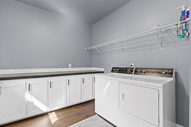 clothes washing area with washer and clothes dryer, cabinets, and dark hardwood / wood-style flooring