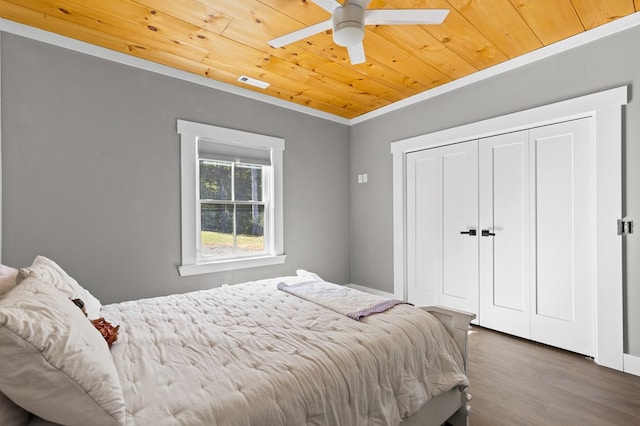 bedroom with wood ceiling, a closet, ceiling fan, dark wood-type flooring, and crown molding