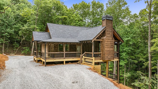 view of front of property with driveway, a chimney, and a shingled roof