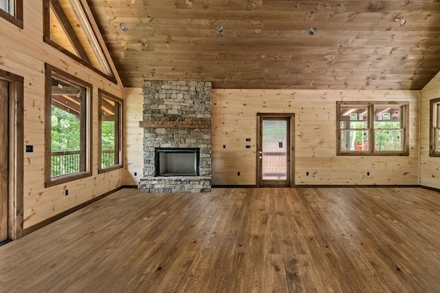 unfurnished living room with wooden walls, a fireplace, wood finished floors, and vaulted ceiling