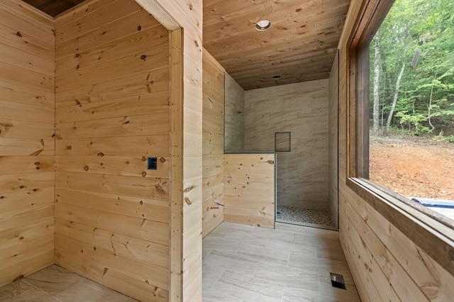 bathroom featuring wooden walls, wood ceiling, visible vents, and a tile shower