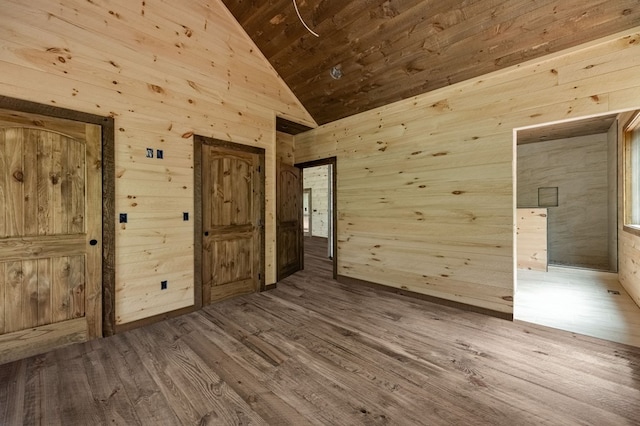 spare room with wooden ceiling, wood finished floors, wood walls, and high vaulted ceiling