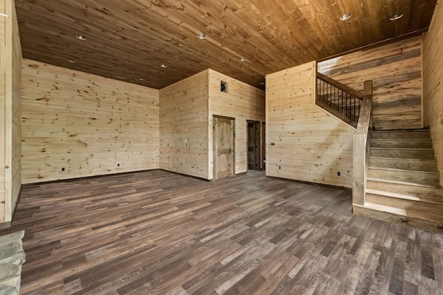 unfurnished living room with dark wood-type flooring, wood ceiling, wood walls, and stairs