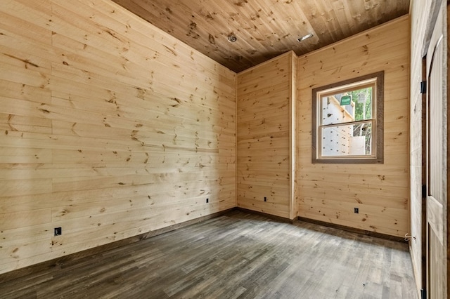 empty room featuring baseboards, wooden ceiling, dark wood-style flooring, and wood walls