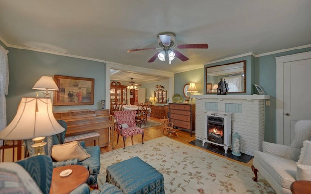 living room with a fireplace, light hardwood / wood-style floors, ceiling fan, and ornamental molding