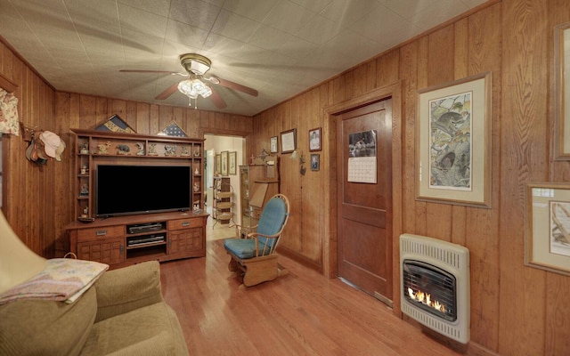 living room featuring heating unit, wood walls, ceiling fan, and light hardwood / wood-style floors