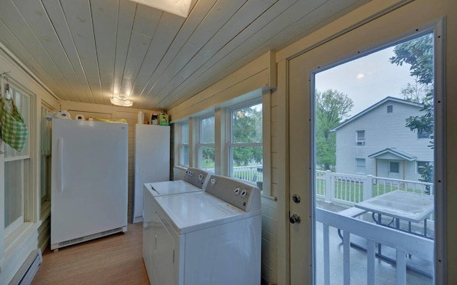 clothes washing area with wood walls, wooden ceiling, light hardwood / wood-style flooring, baseboard heating, and washing machine and clothes dryer