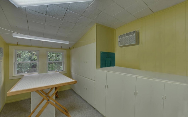 basement featuring light colored carpet and a wall mounted AC