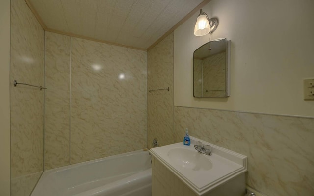 bathroom featuring a tub to relax in, crown molding, vanity, and tile walls