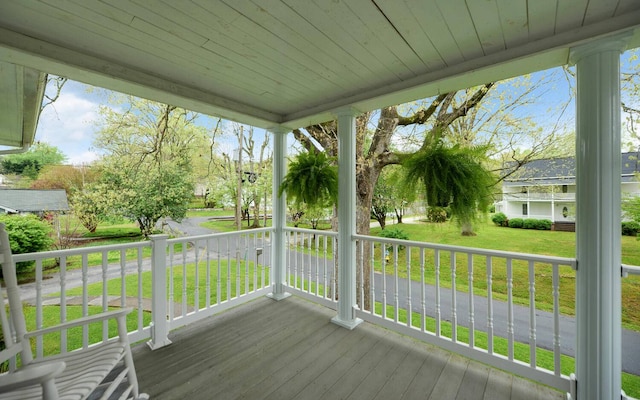 wooden terrace with covered porch and a yard