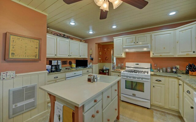 kitchen with white gas range, white cabinetry, heating unit, and a kitchen island