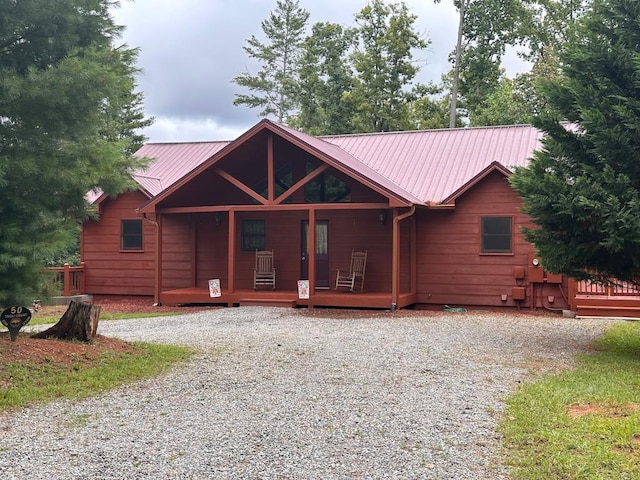 view of front of house featuring a porch, metal roof, and driveway