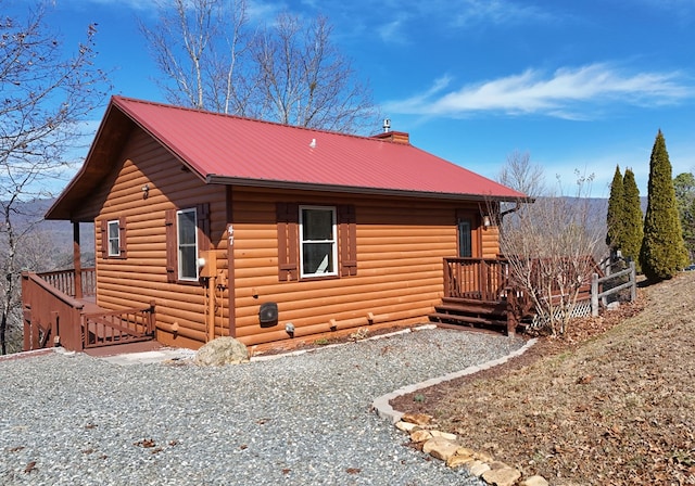 exterior space featuring gravel driveway, a chimney, and metal roof