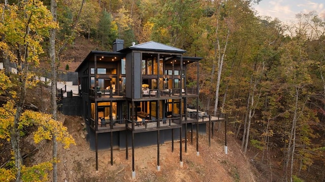 back of house featuring a deck, a forest view, and a chimney
