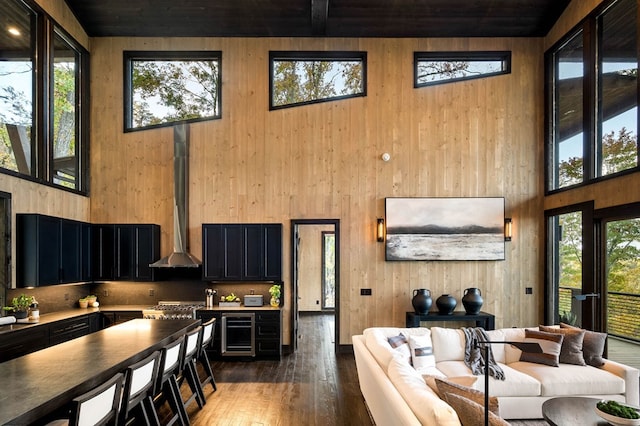 living area with wooden walls, wooden ceiling, a towering ceiling, and wood finished floors