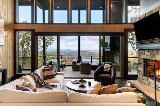 living area featuring wooden walls, a fireplace, a towering ceiling, and wood-type flooring