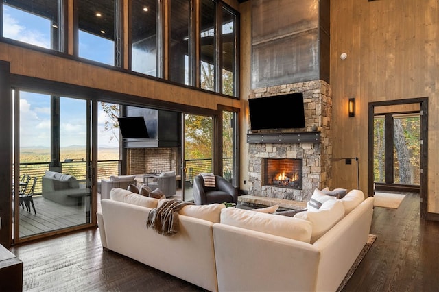 living room with wooden walls, a fireplace, a towering ceiling, and wood finished floors