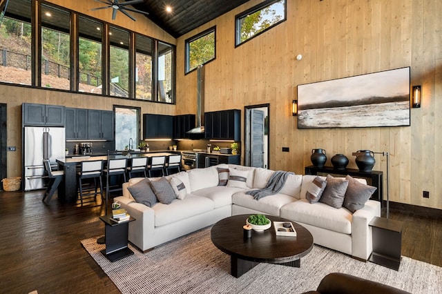 living room with dark wood finished floors, wooden walls, and high vaulted ceiling
