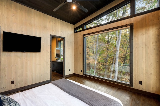 bedroom featuring wood finished floors, wooden walls, baseboards, and lofted ceiling