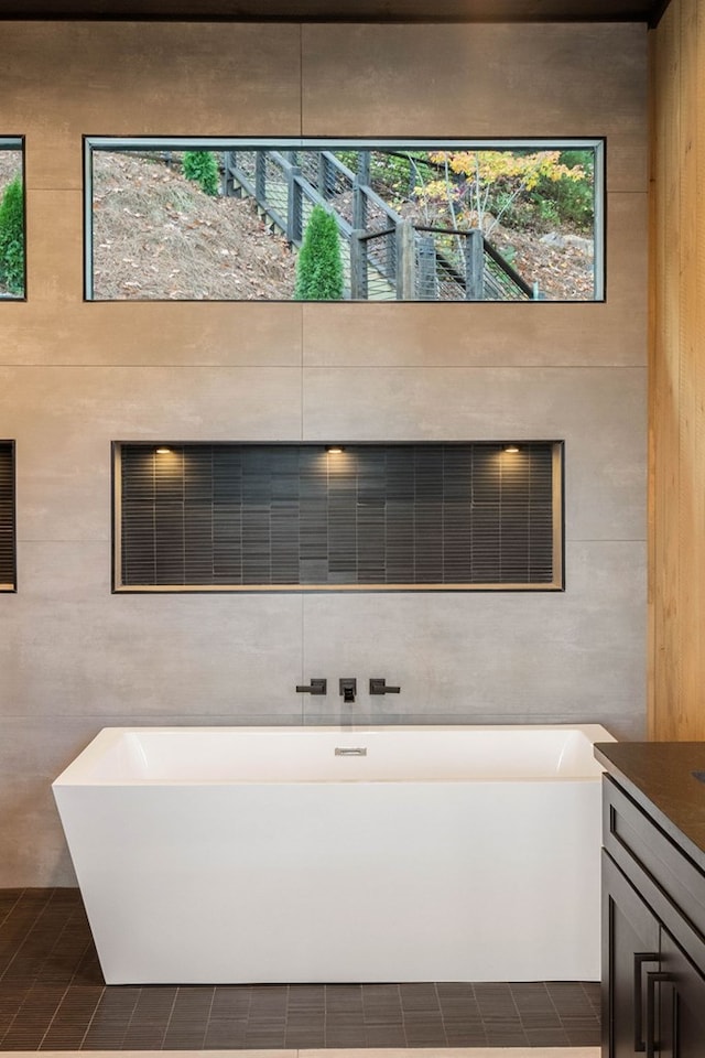 full bathroom with wooden walls, tile patterned floors, vanity, and a freestanding bath