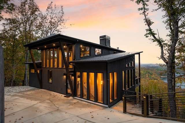 back of property with fence, a patio, and a chimney
