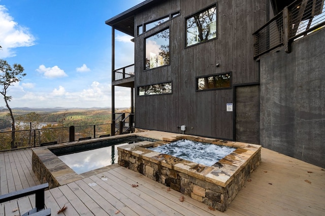 wooden deck with a mountain view and an in ground hot tub