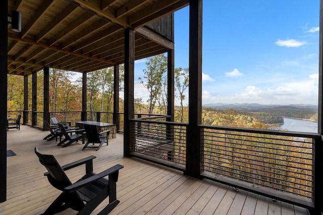 wooden deck with a water view and outdoor dining space