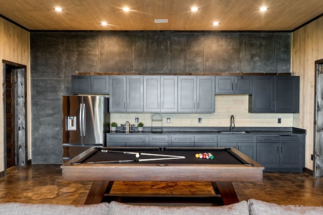 kitchen featuring stainless steel fridge with ice dispenser, dark countertops, a sink, and pool table