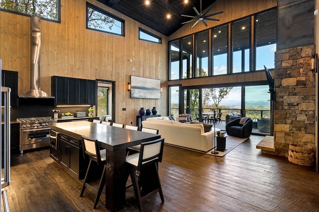 dining room featuring wooden walls, a ceiling fan, dark wood-type flooring, and high vaulted ceiling