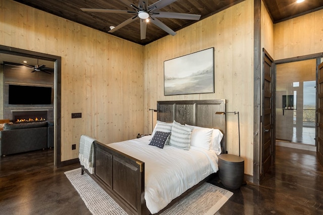 bedroom featuring finished concrete floors, wooden walls, wood ceiling, and a warm lit fireplace