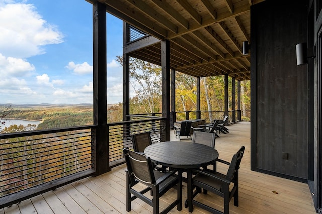 wooden terrace with a water view and outdoor dining space