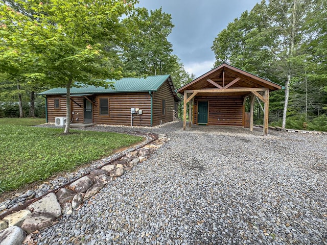 view of front facade featuring faux log siding, gravel driveway, a carport, and metal roof