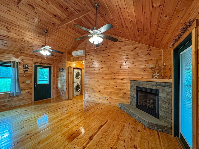 unfurnished living room featuring stacked washer and clothes dryer, wood ceiling, hardwood / wood-style flooring, a ceiling fan, and a fireplace