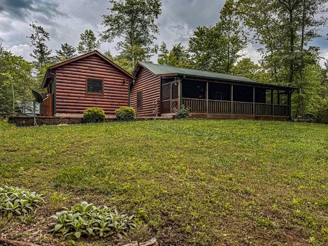 back of property with a sunroom, faux log siding, and a yard